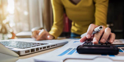 Lady calculating inheritance tax with a laptop, paperwork and calculator