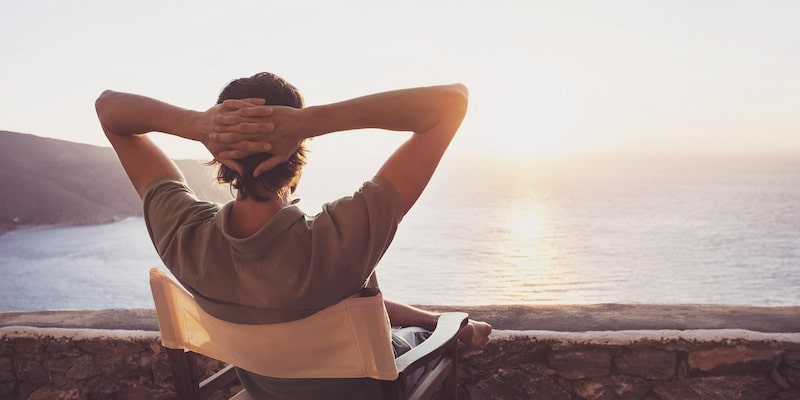 Image of a man sitting back and relaxing looking into the sunset over the ocean. It's meant to symbolise a convenient sale if you choose to sell to a quick-sale company. 